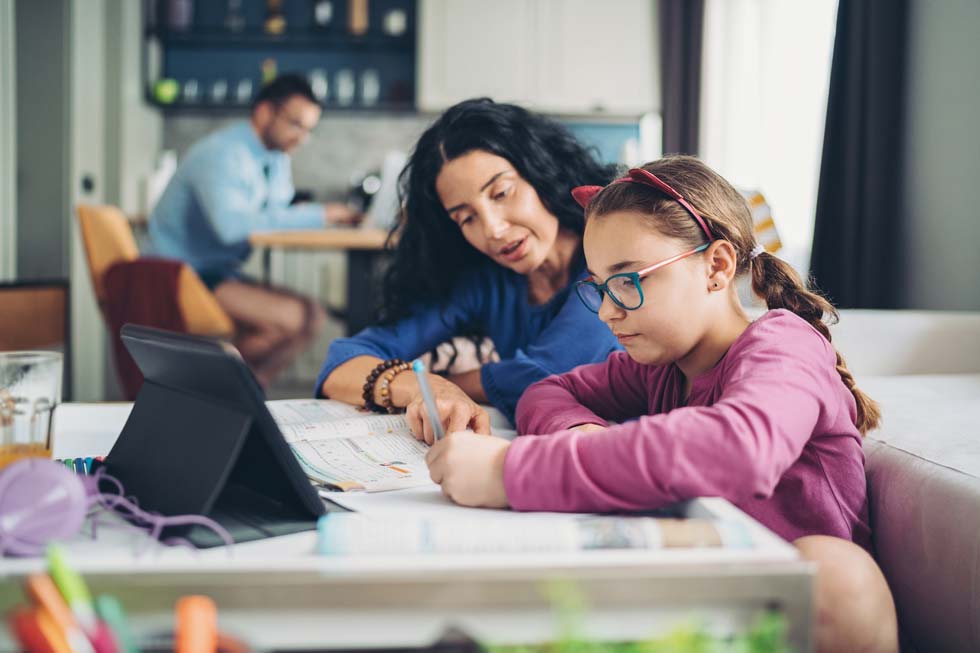 mother and daughter sitting at dining table doing homework