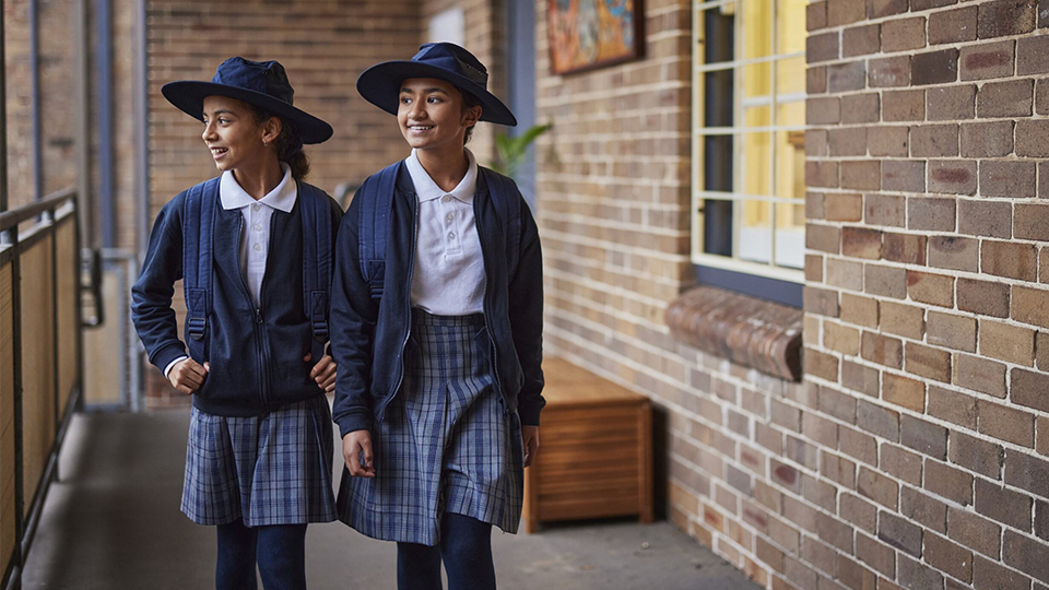 Two girls in school uniform walking down the school hallway