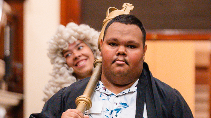 a boy wearing a black gown and holding a pole