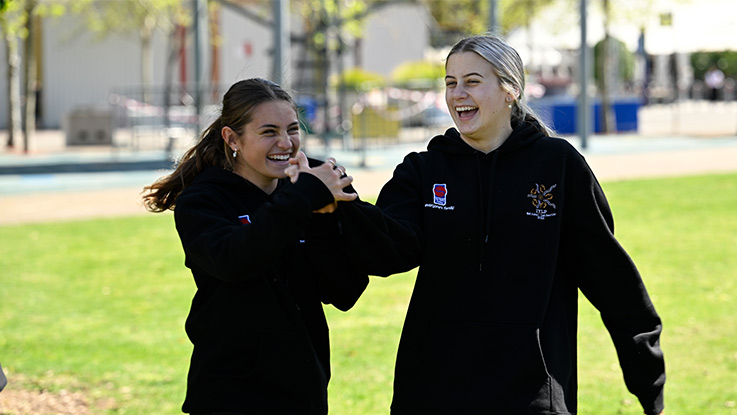 two wearing black hoodies laughing in a park together