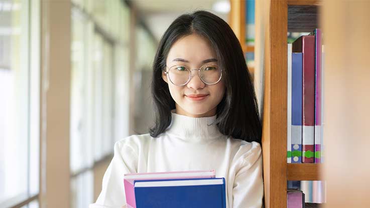 Student in a library holding books