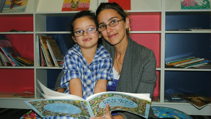 Mother with daughter in her school uniform reading