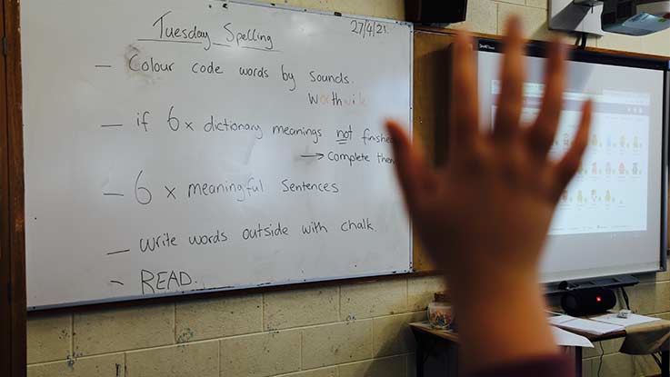 A student hand is raised in classroom setting