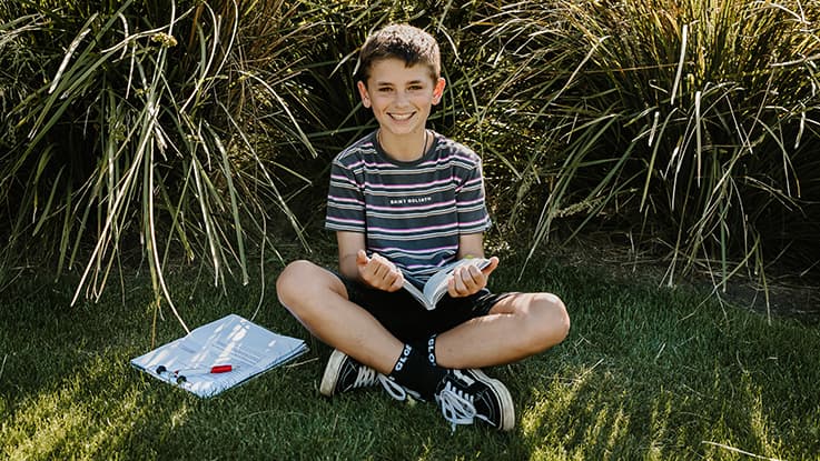 Child sitting on grass with book