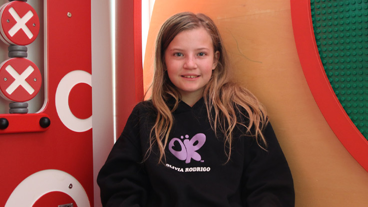 a young school girl wearing a black jumper sitting in a playground