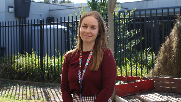 a smith family learning for life coordinator wearing a maroon sweater and wearing a lanyard with indigenous art print