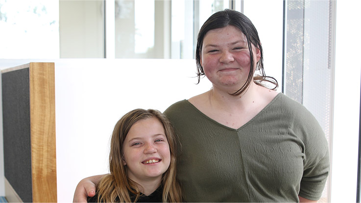 two sisters standing side by side smiling together
