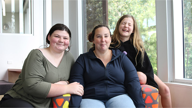  a mother smiling with her daughters together on a lounge