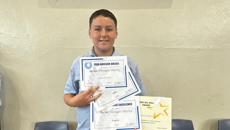 school boy holding his certificate in class