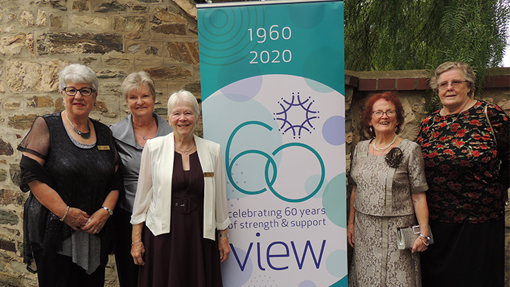 a group of ladies standing next to a pull up banner saying 1960-2020 60 years of view