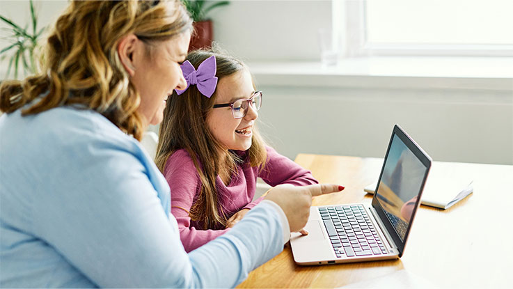 a lady helping a child with school work on her laptop