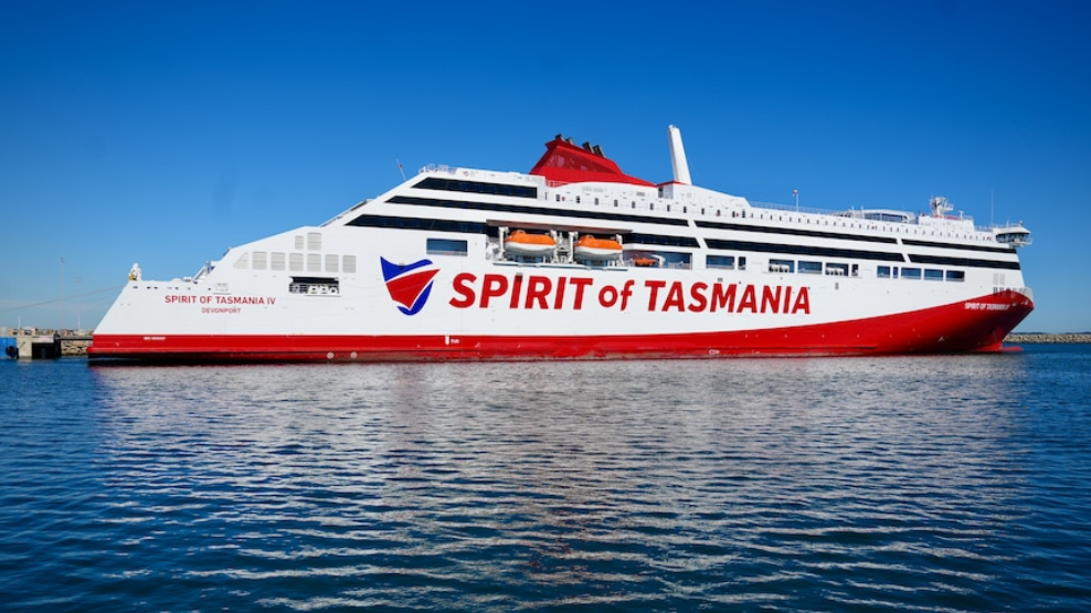 Spirit of Tasmania ferry docked on calm water, with a white and red exterior under a clear blue sky.