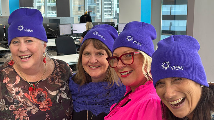four ladies wearing purple view beanies
